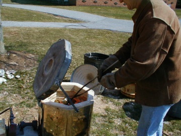 Milt Friedly pulls pottery from kiln with tongs.